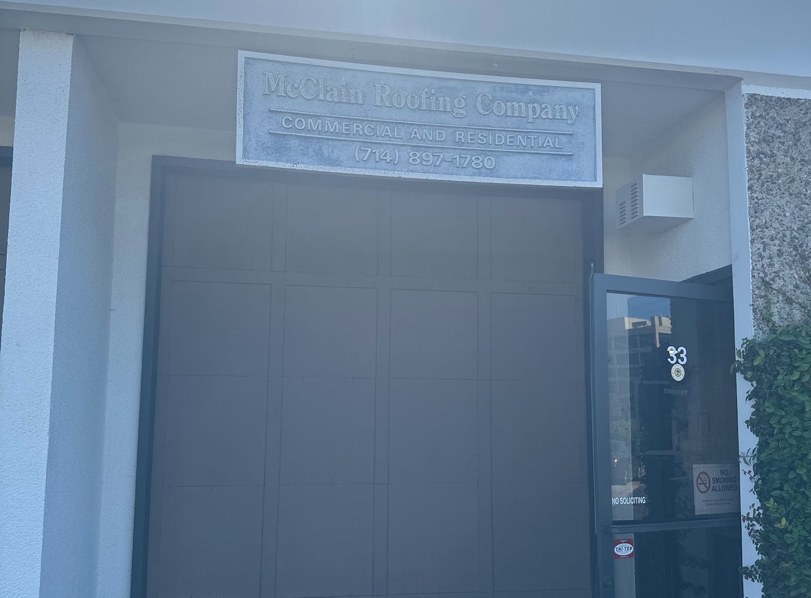 The entrance to Suite 33, with a sign over the door that reads McClain Roofing Company, Commercial and Residential, and the phone number.
